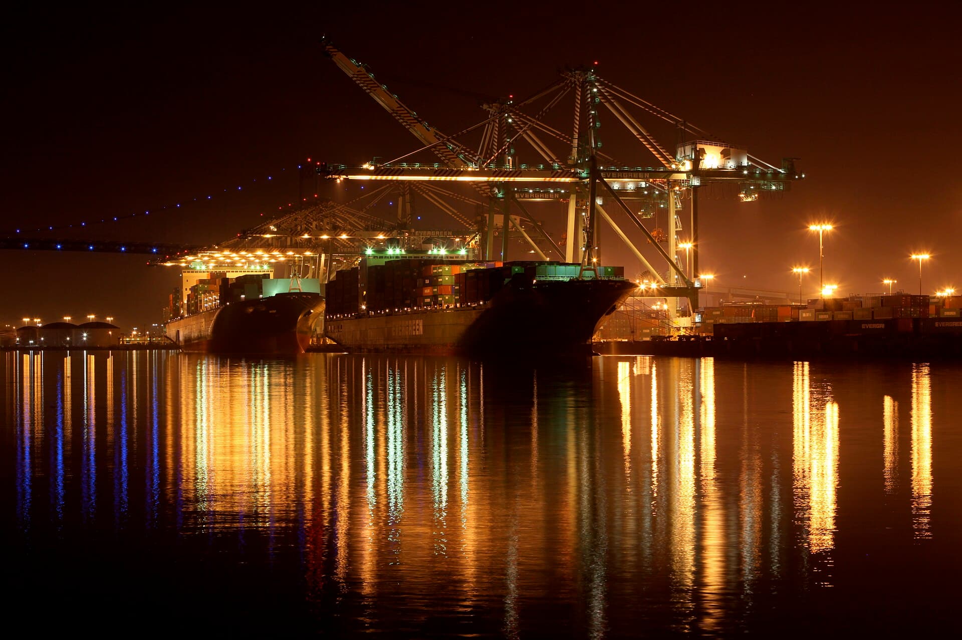 Evergreen container ships under lit cranes at the Port of Los Angeles at night