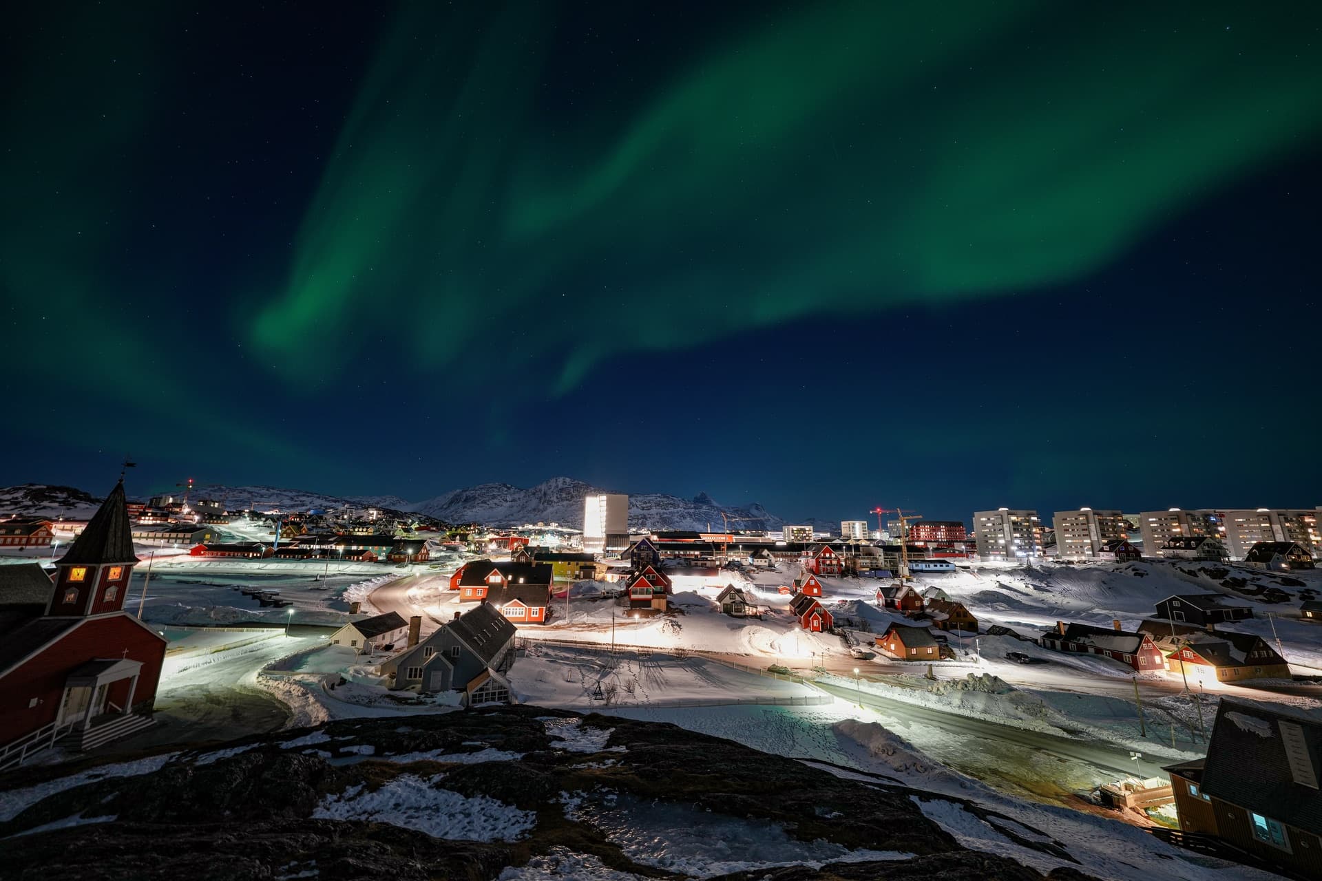 The skyline of Nuuk, Greenland's capital, at night under the northern lights